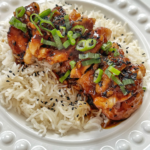 Close up of honey ginger chicken in a white bowl over rice.