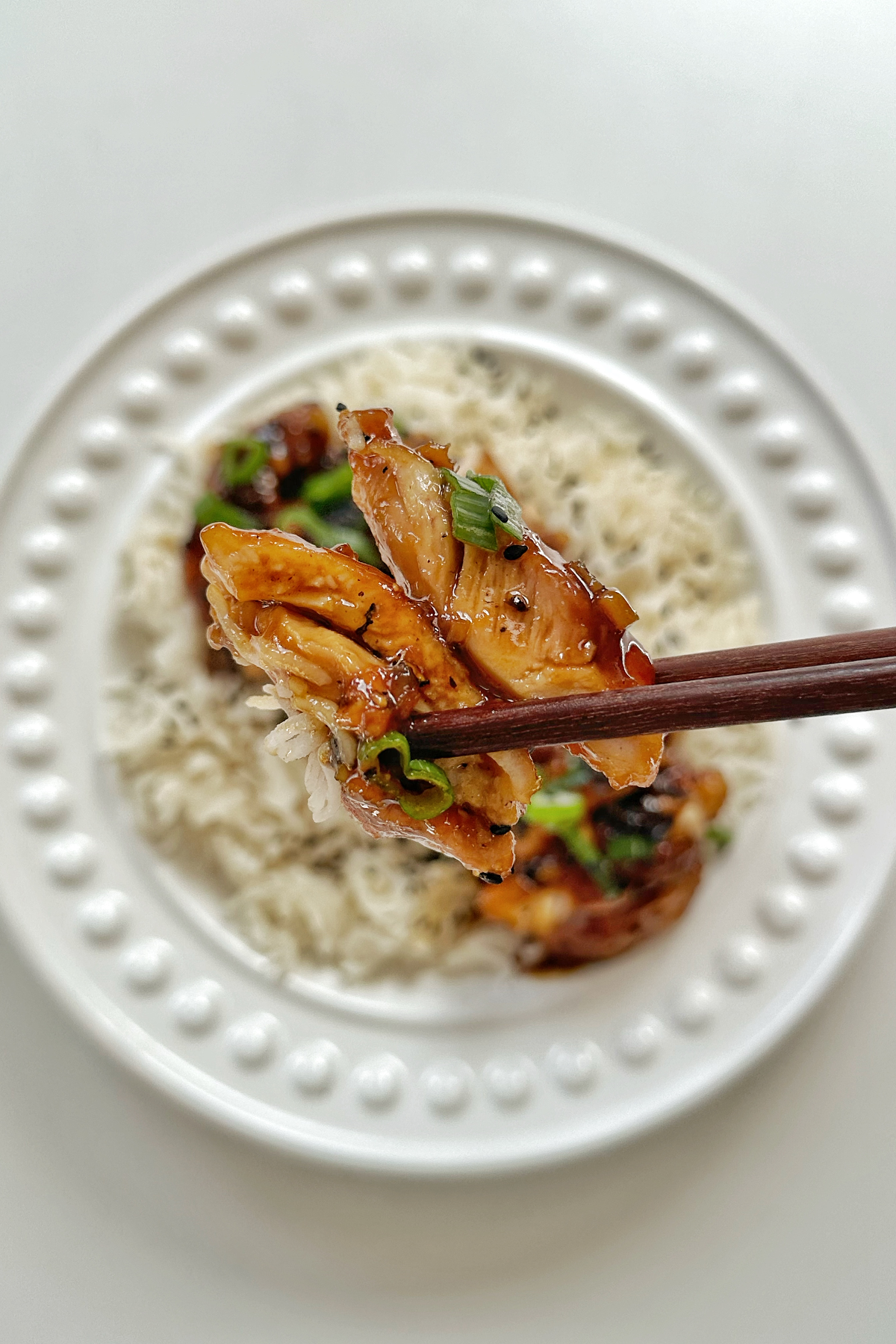 Close up of a piece of honey ginger chicken with chopsticks.