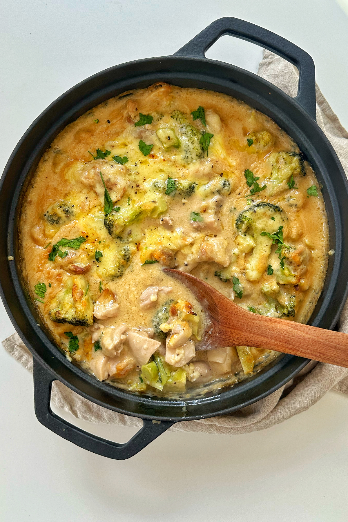 Chicken casserole in a black dish with a wooden spoon. 