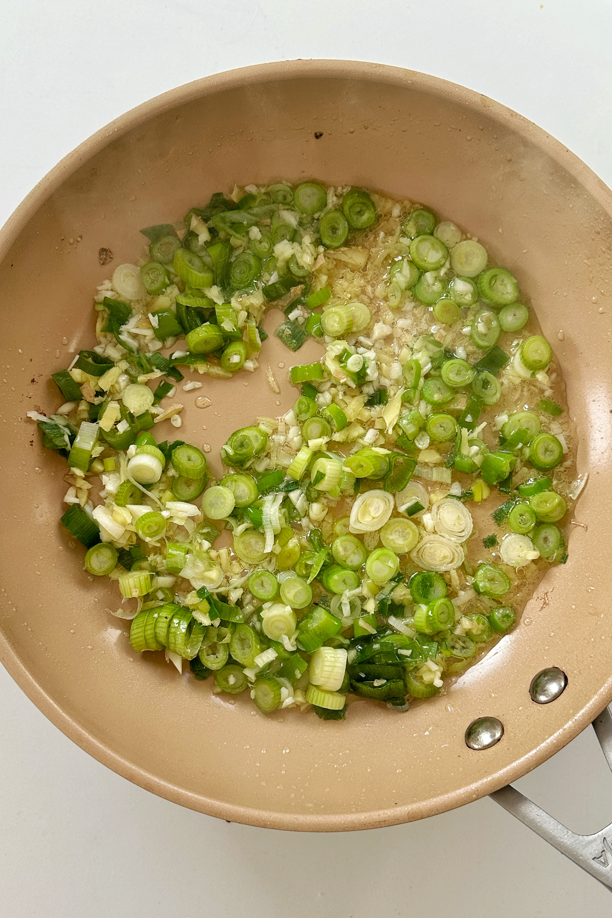 Frying scallions with garlic and ginger in frying pan.