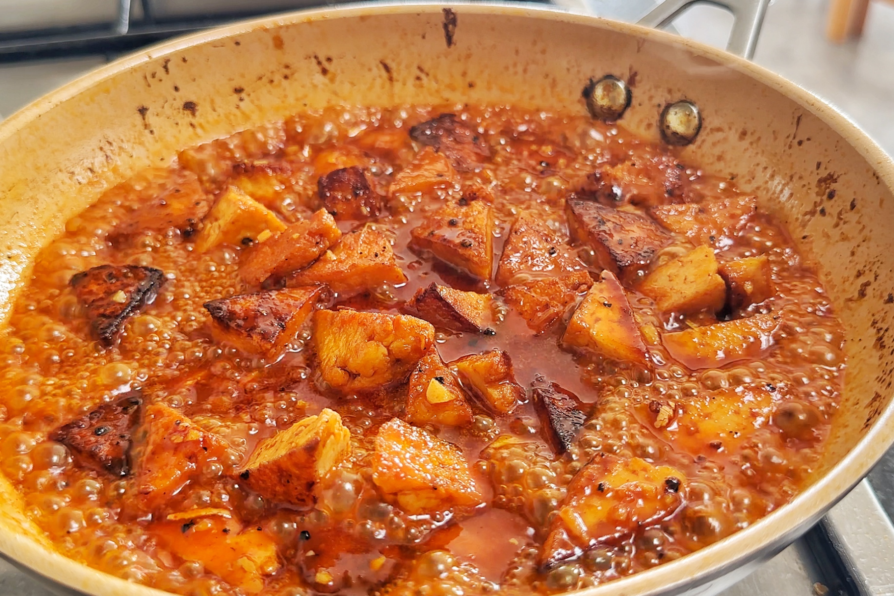 Frying tofu with a gochujang sauce in a pan.