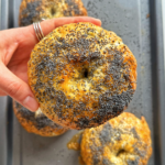 Hand holding up a poppy seed bagel.