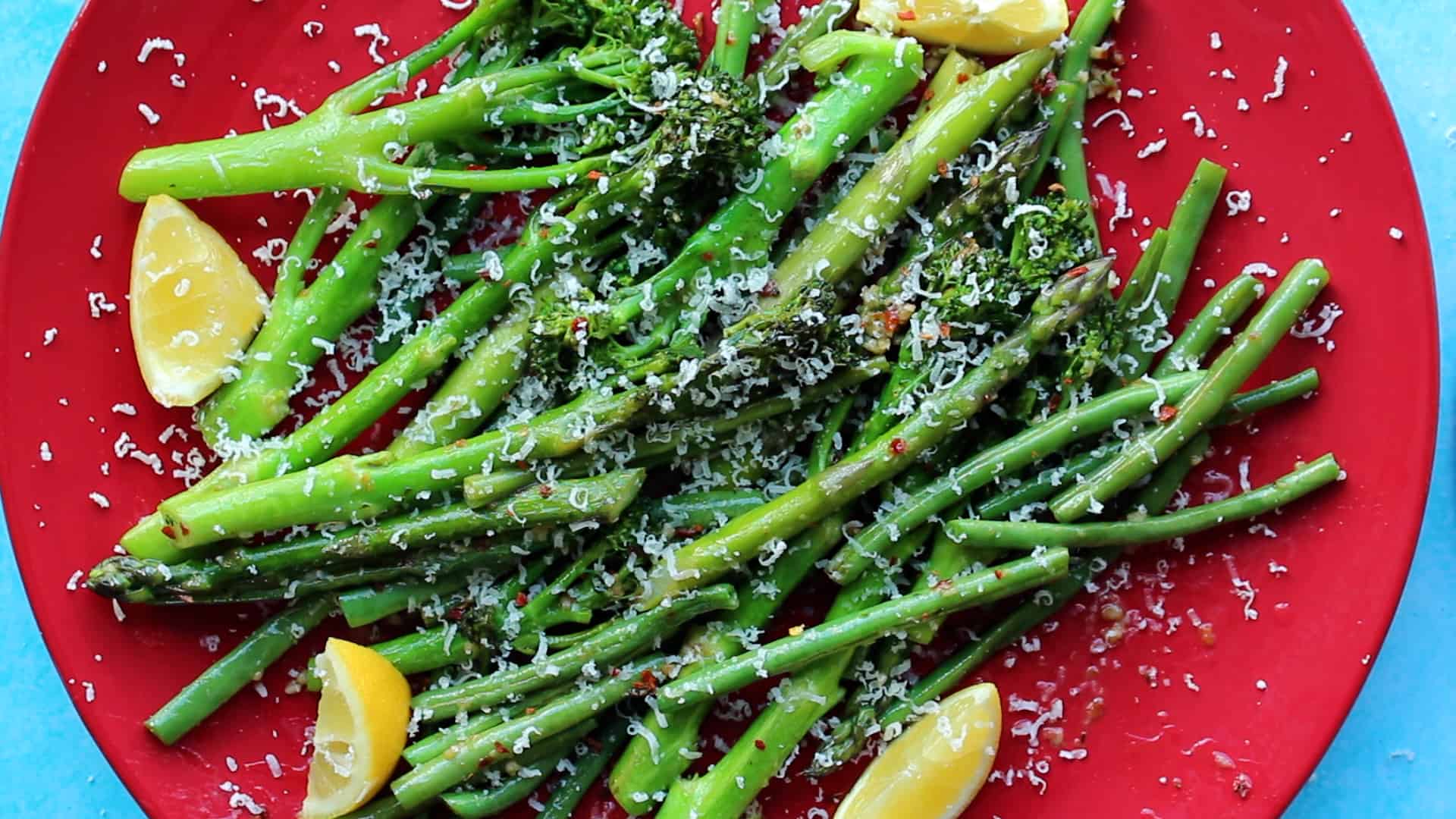 Roasted tenderstem broccoli on a red background.