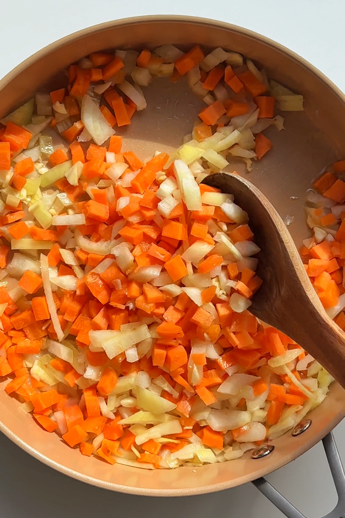 Frying onion, garlic, and carrots in a pan.