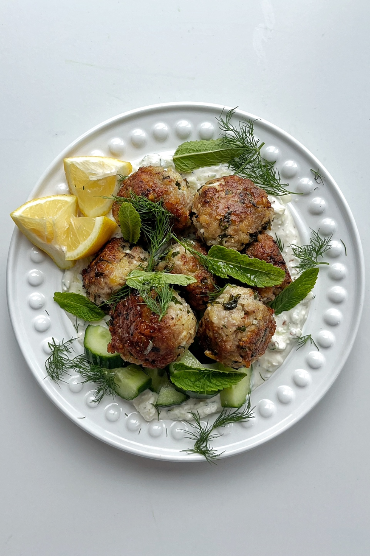 A whole plate of Greek meatballs with lemon, dill, and mint.