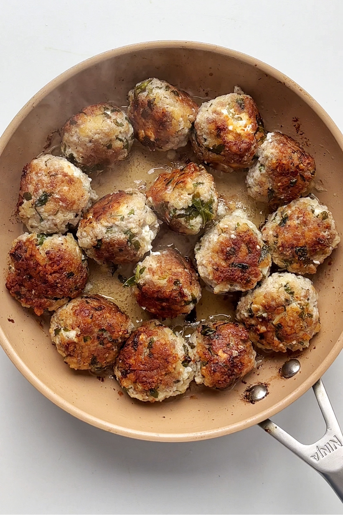 Cooking meatballs in a frying pan or skillet until golden brown.