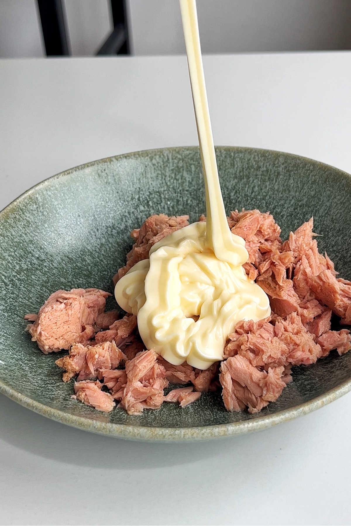 Squeezing mayonnaise into a bowl of tuna.