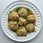 Pan fried lemongrass and beef dumplings on a white plate.