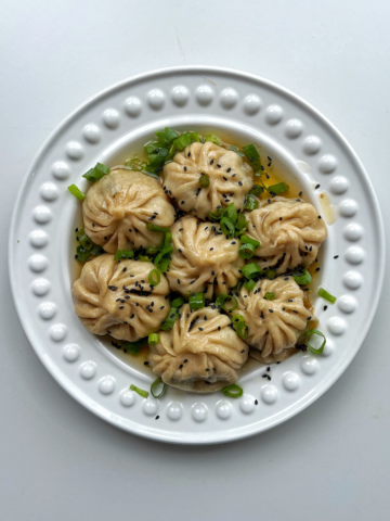Pan fried lemongrass and beef dumplings on a white plate.