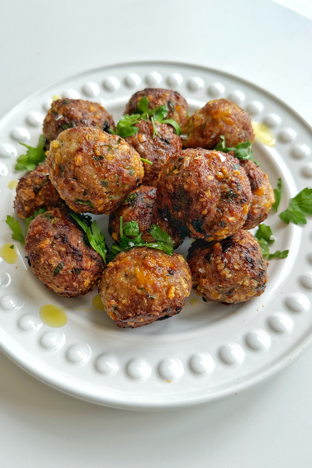 Side angle of air fryer turkey meatballs on a white plate.
