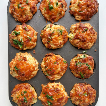 Bacon and cheese muffins in a baking tin on a white background.