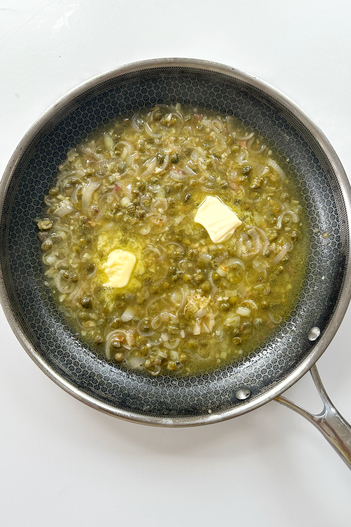 Making a sauce with butter, chicken stock, and lemon juice.
