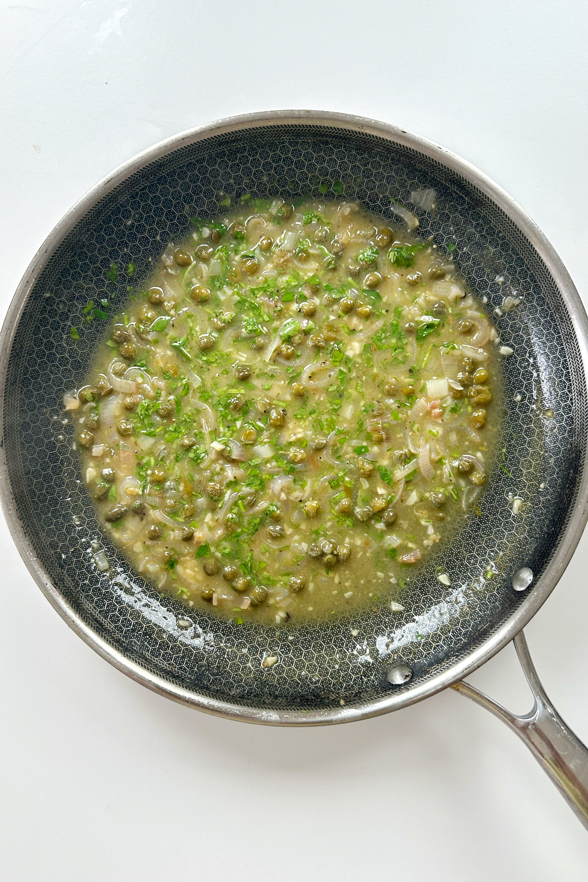 A piccata sauce in a frying pan or skillet.