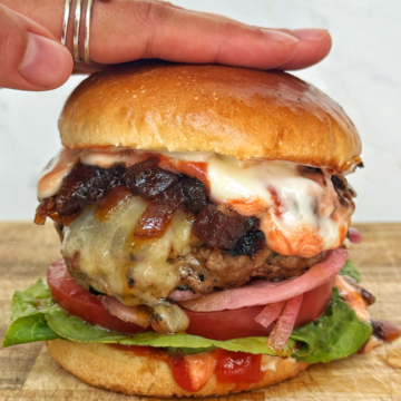 Hamburger patty in a bun with lettuce, tomato, onion.