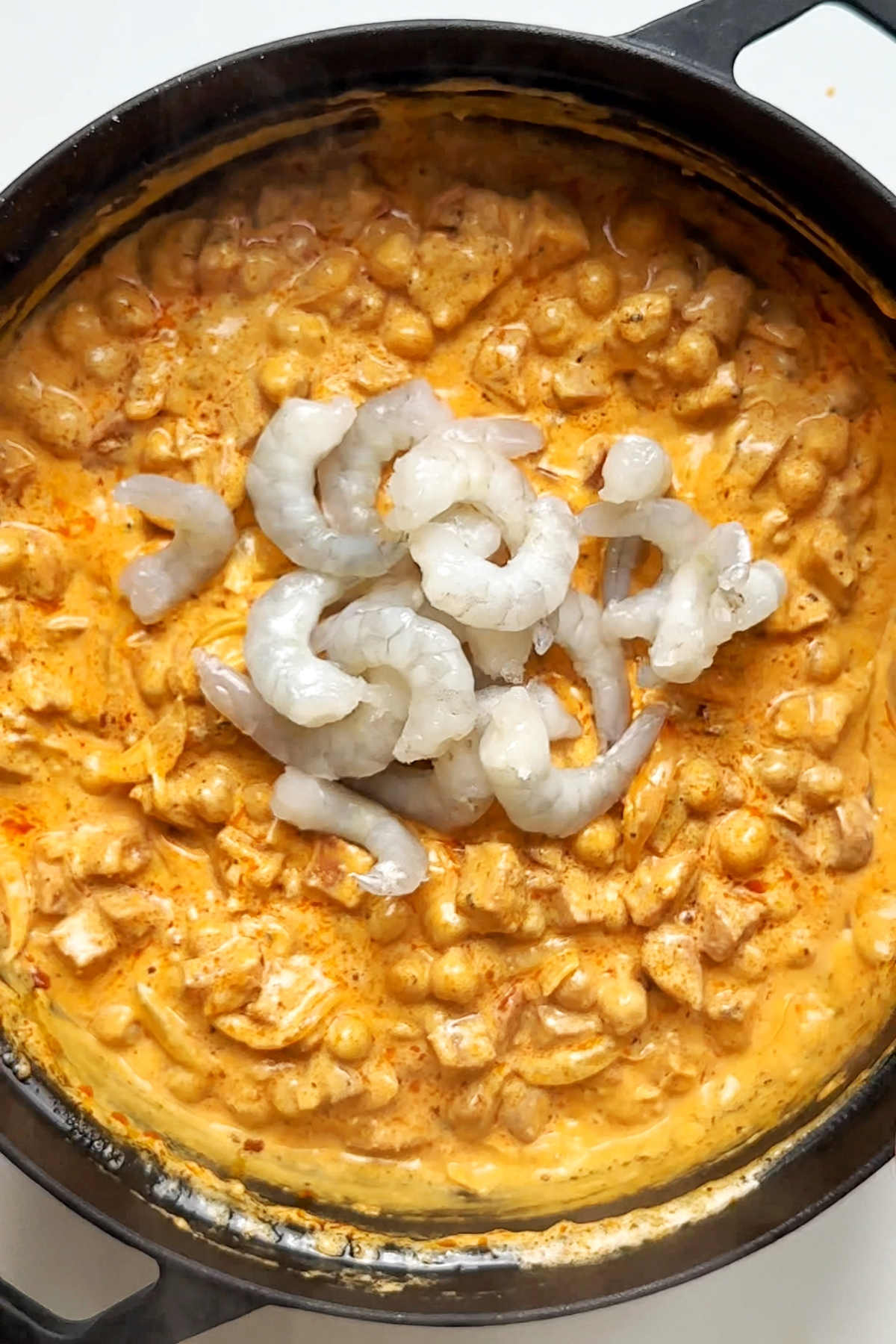 Adding prawns into a chorizo and chickpea pie.