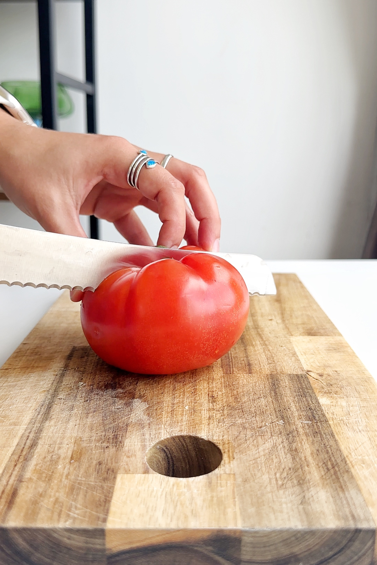 Slicing a tomato on a wooden chopping board.