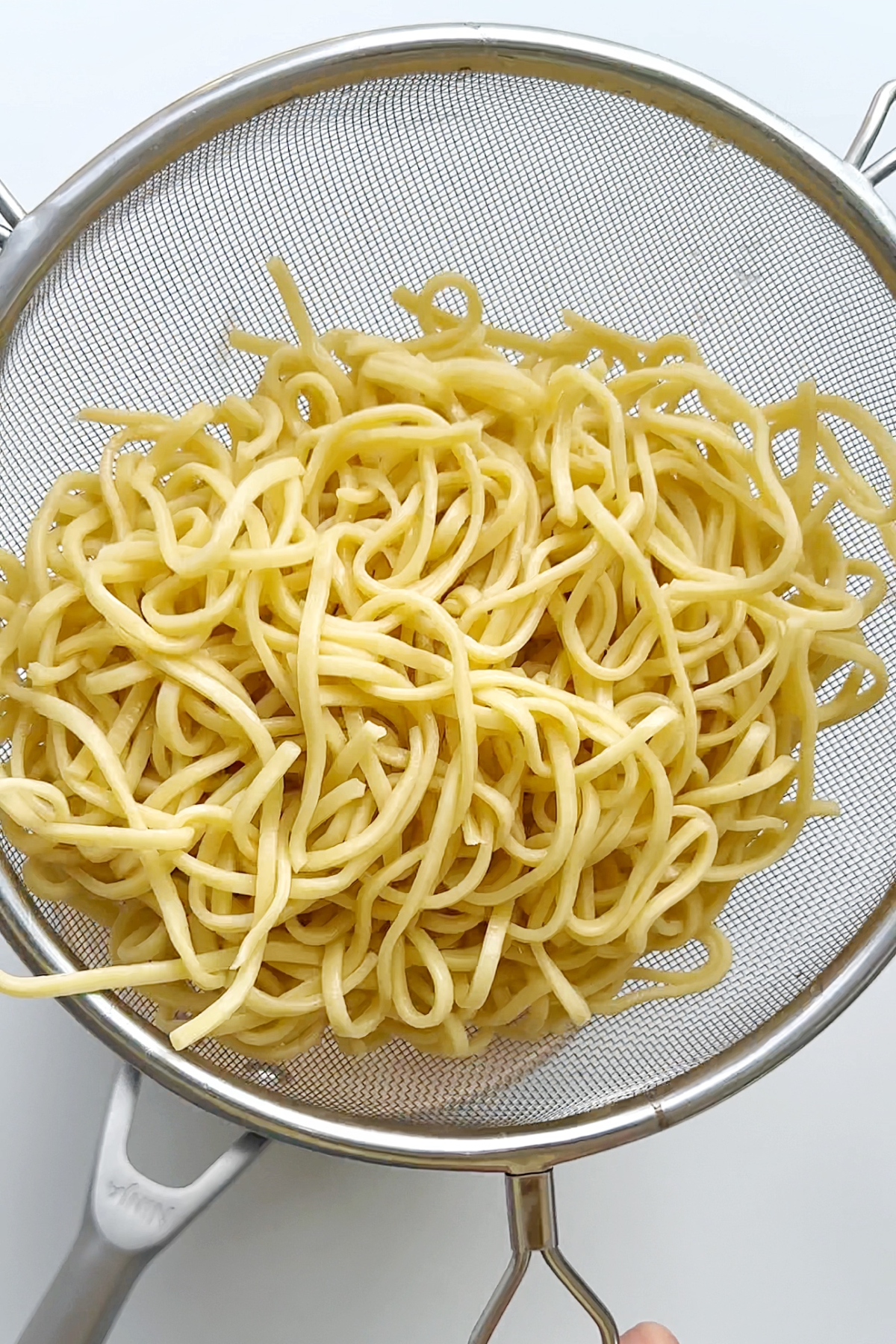 Straining noodles in a sieve.