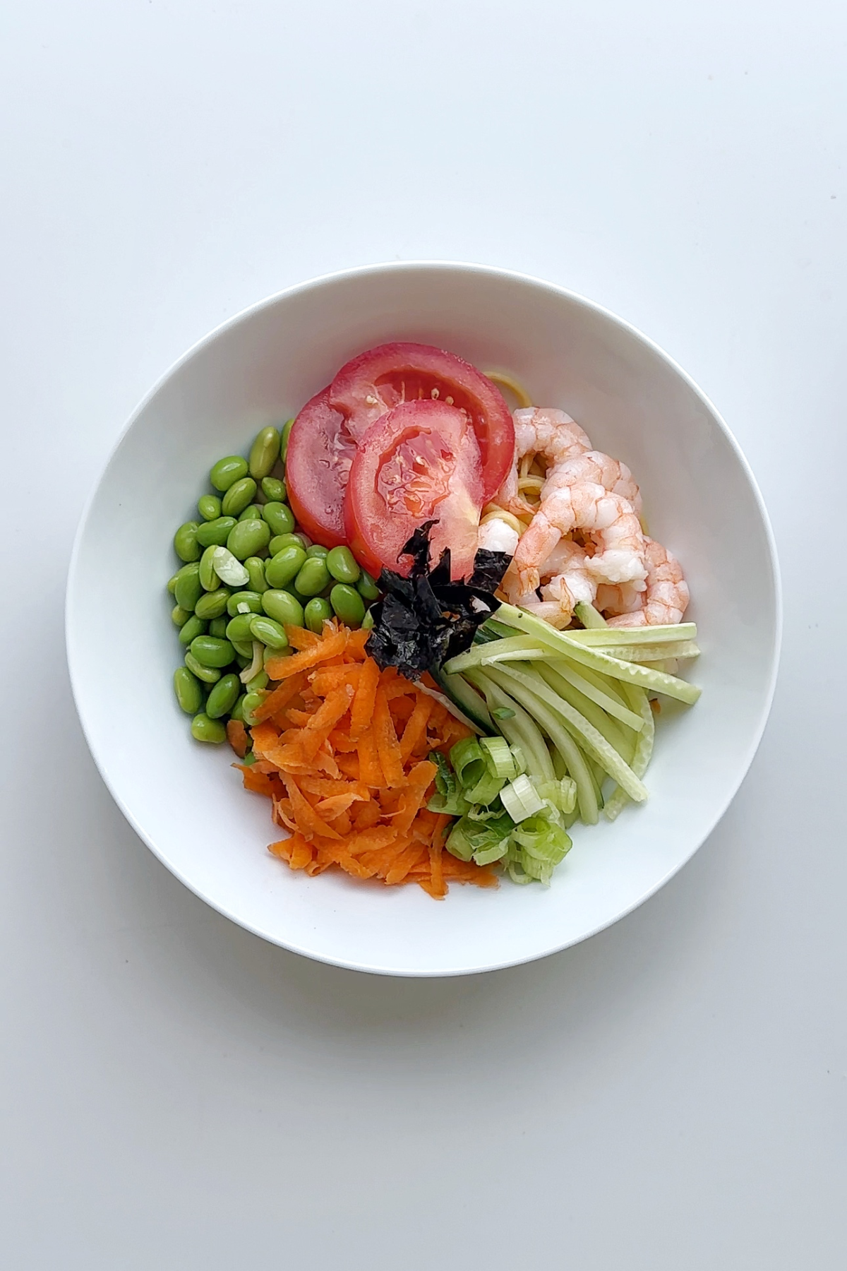 Assembled cold ramen noodles in a white bowl.
