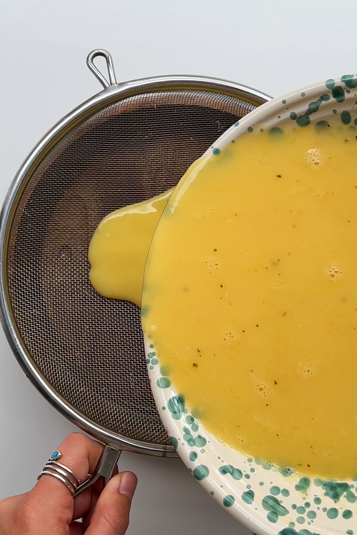 Sieving eggs into a bowl.