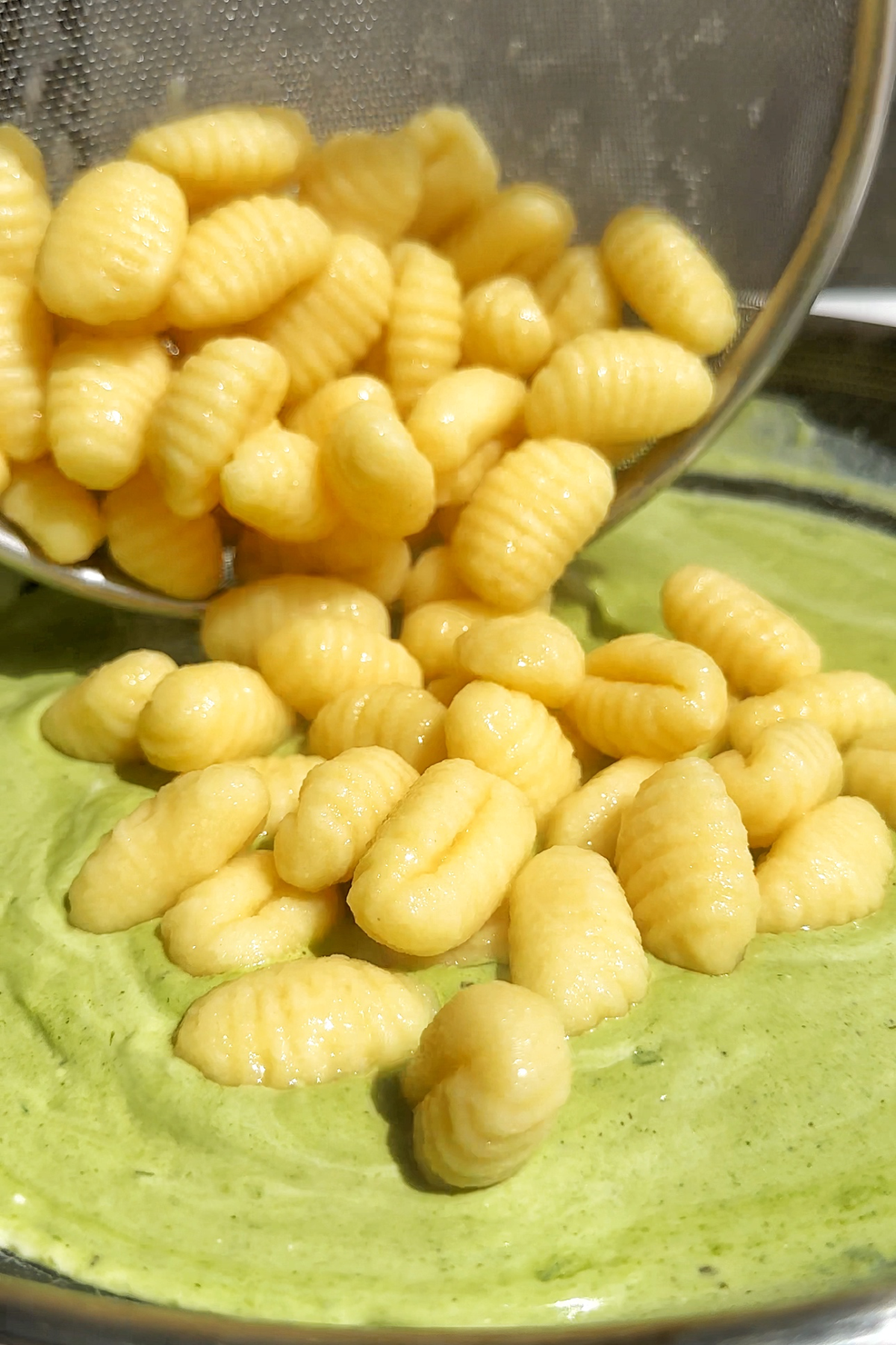 Adding gnocchi into homemade pesto.