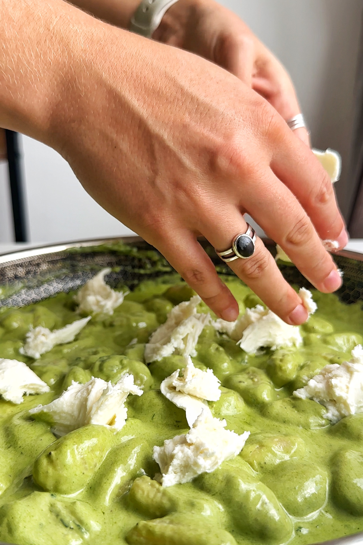 Tearing mozzarella and placing it into the pesto gnocchi.