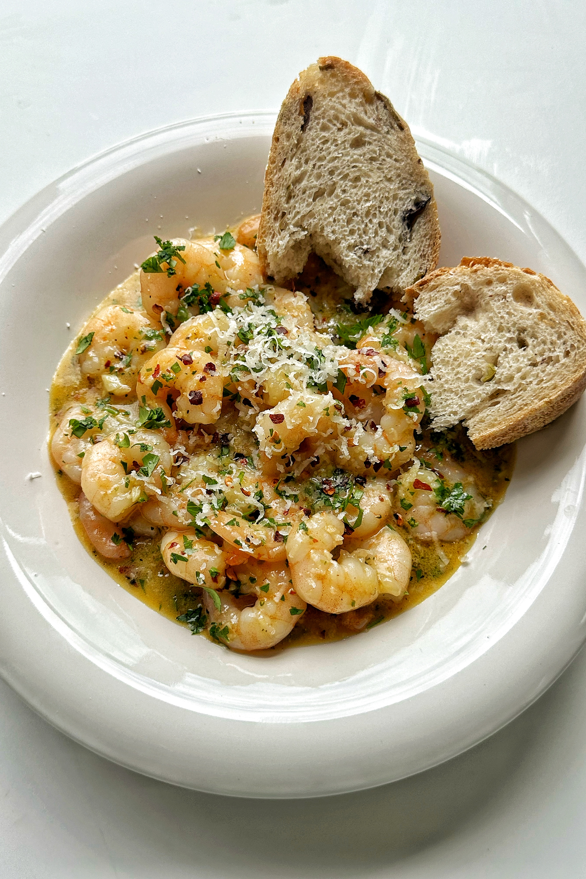 Shrimp scampi without wine, with bread in a white bowl.