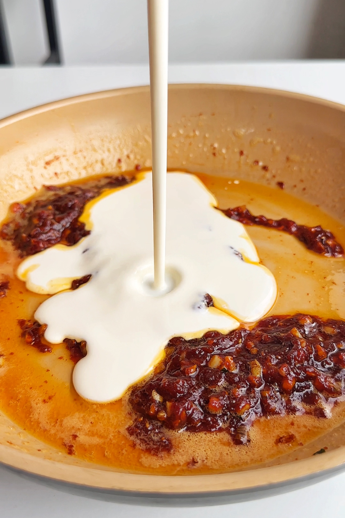 Adding cream into a pan with gochujang, butter, and garlic.
