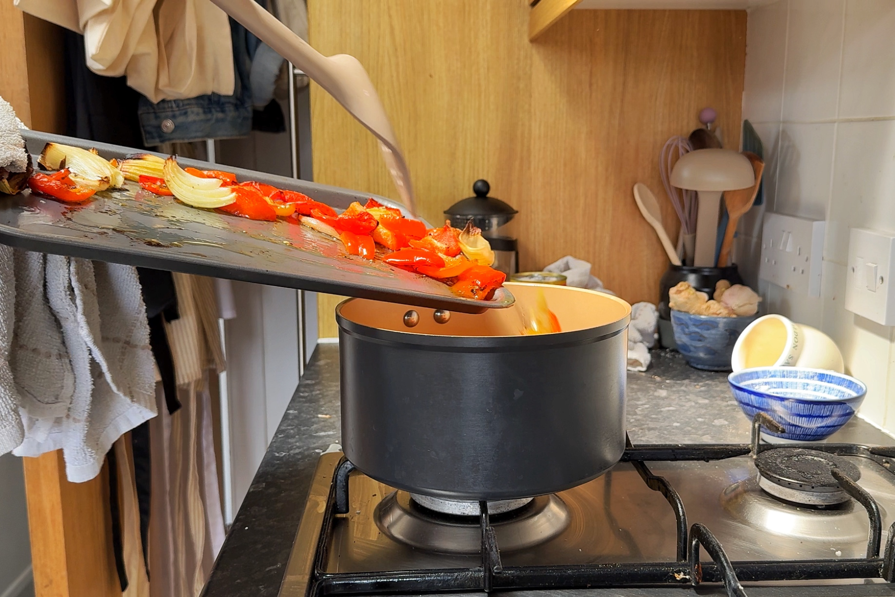 Adding roasted vegetables into a pan.