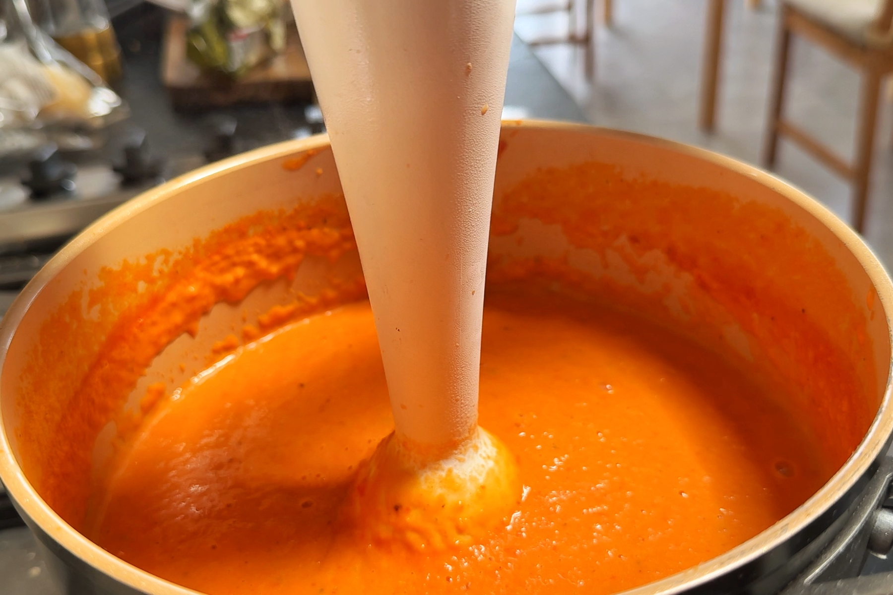 Blending roasted red pepper soup in a pan.