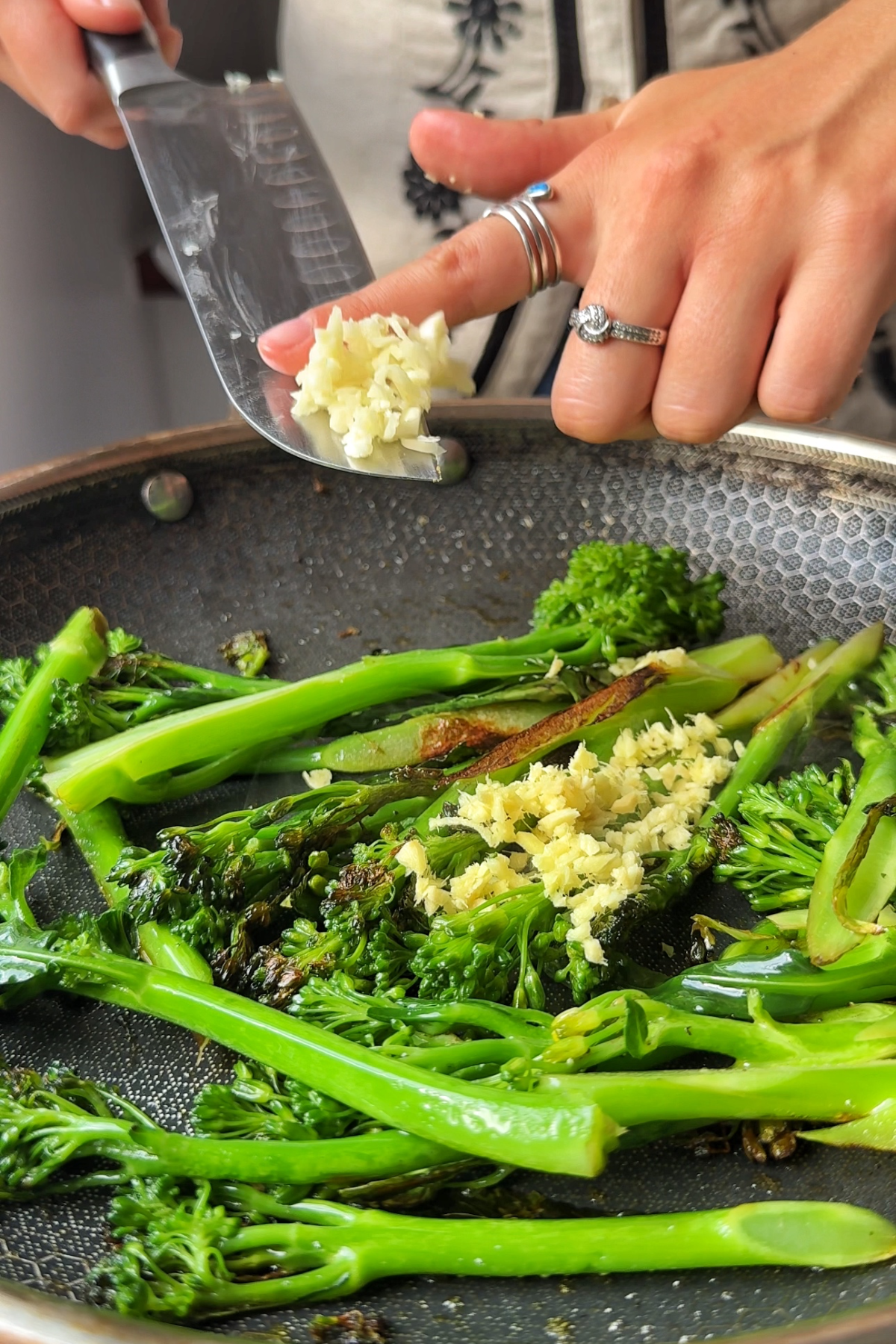 Adding garlic and ginger into stir-fried broccolini.