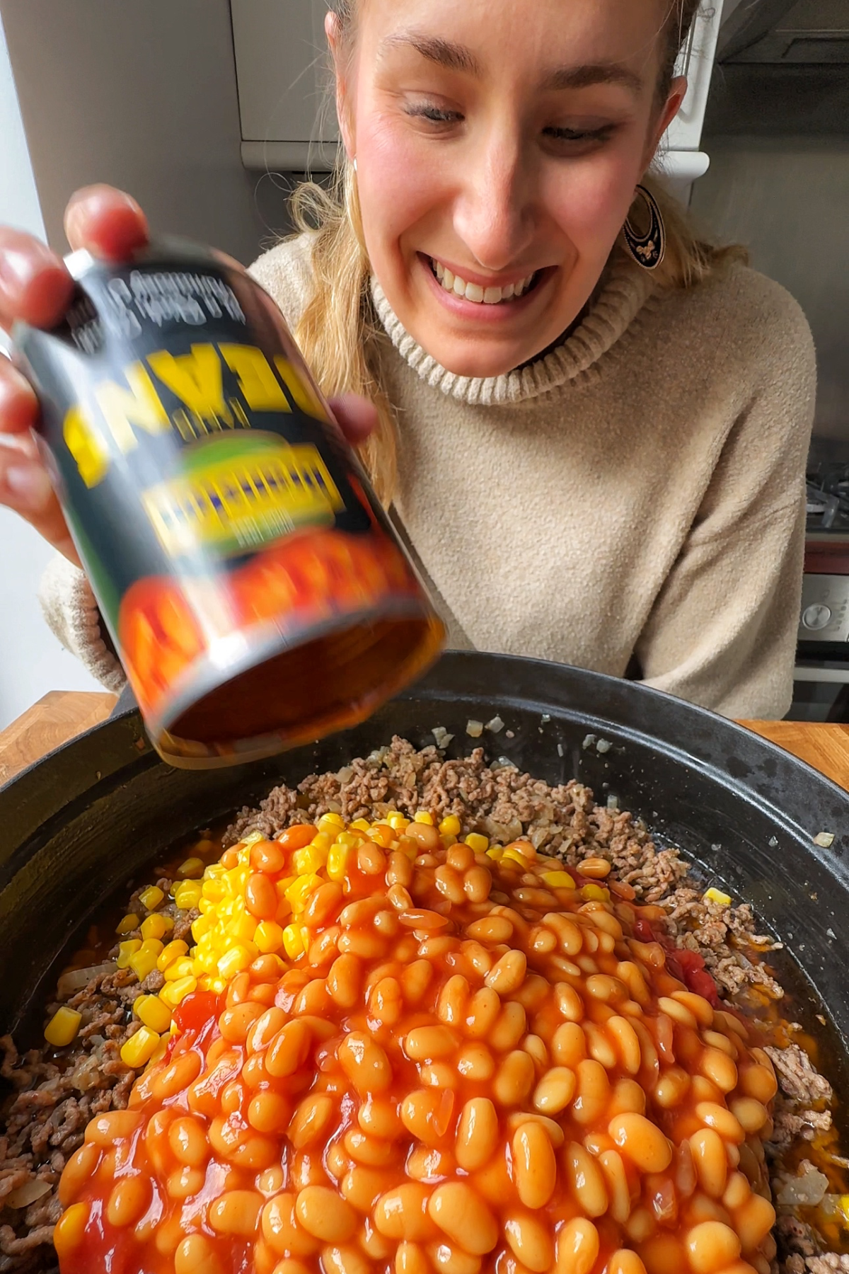 Adding baked beans into the skillet.