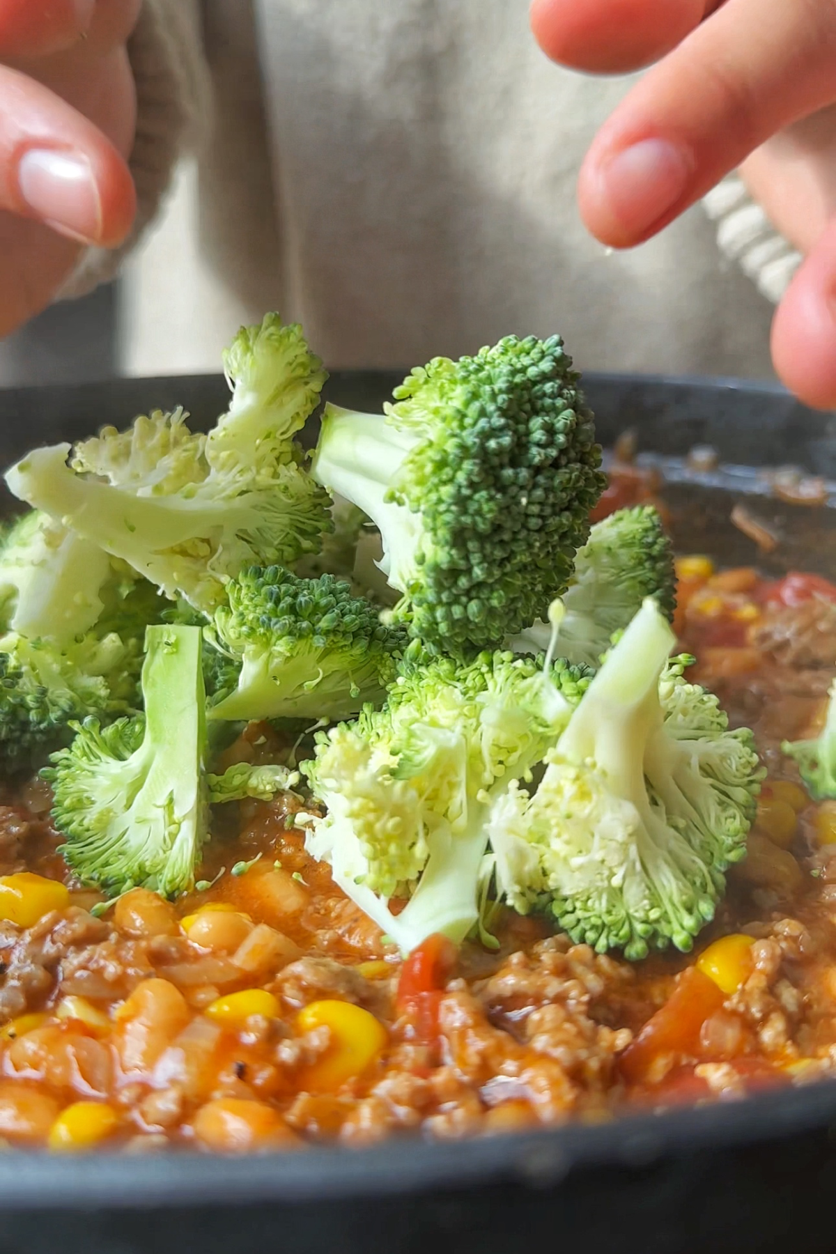 Adding broccoli into the cowboy casserole skillet.