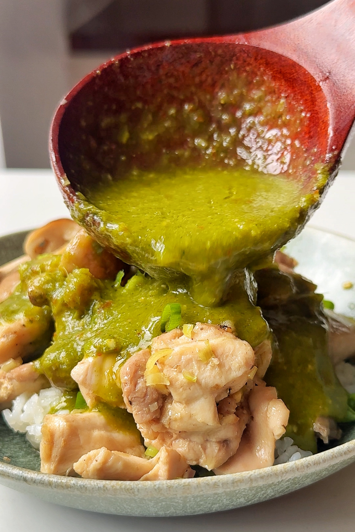 Pouring coriander sauce over the steamed chicken.