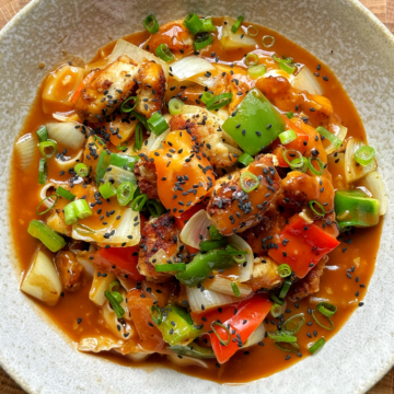 Sweet and sour chicken noodles in a white bowl.