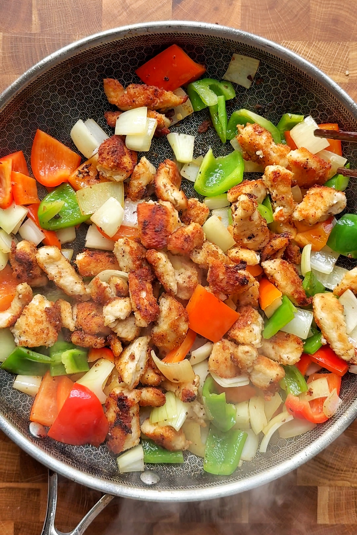 Frying chicken with green and red bell peppers.