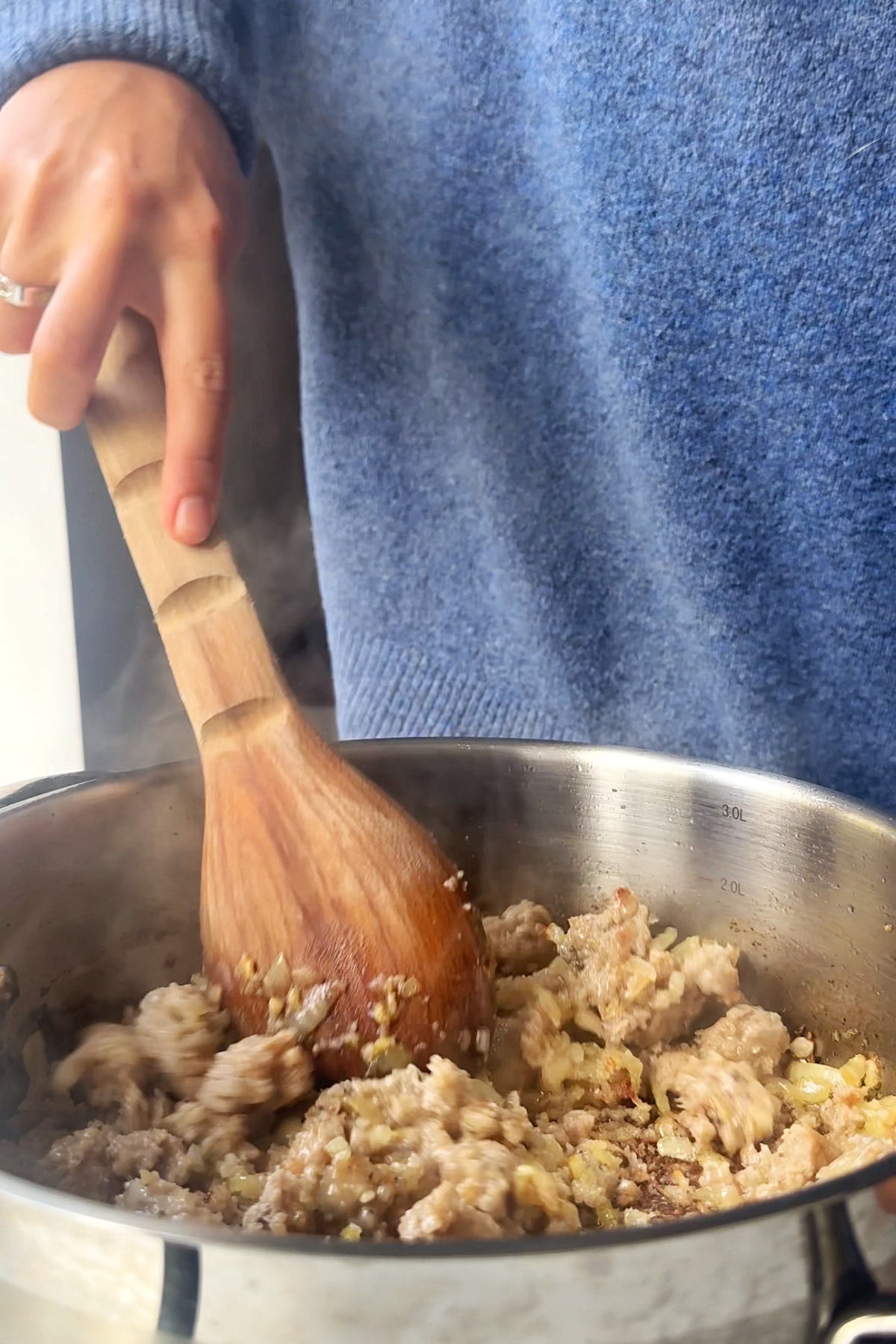 Stirring sausages into the pan.