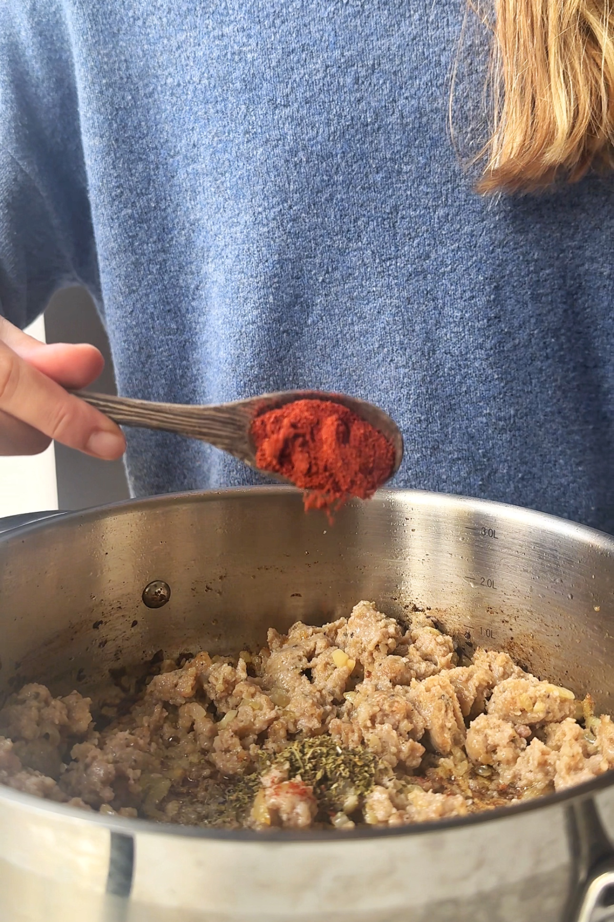 Adding seasonings into the sausage kale and white bean soup.