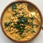 Kale and white bean sausage soup on white background.