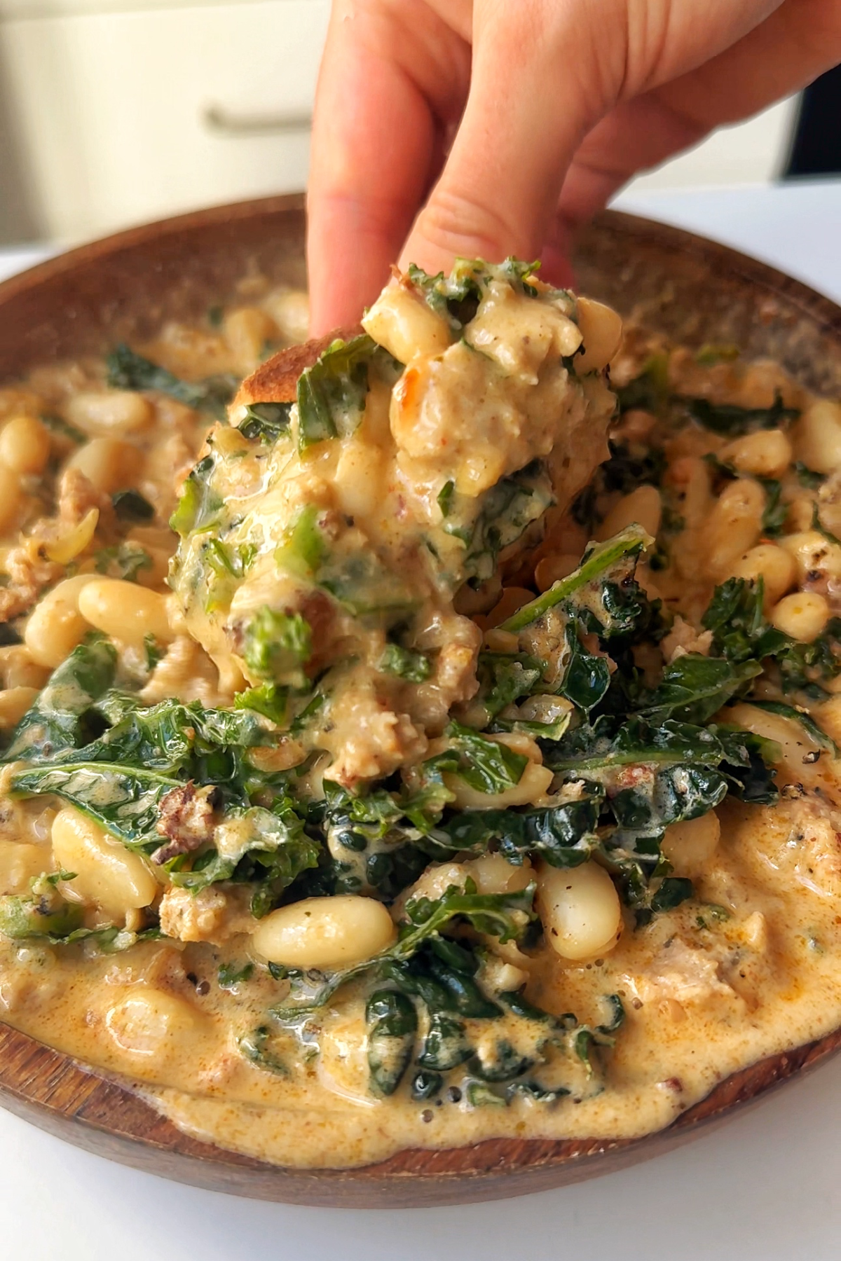 Scooping up kale and white bean sausage soup with bread.