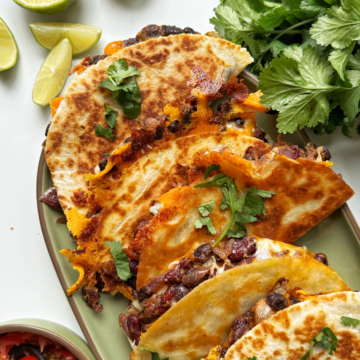 Bean tacos stacked on a green platter.
