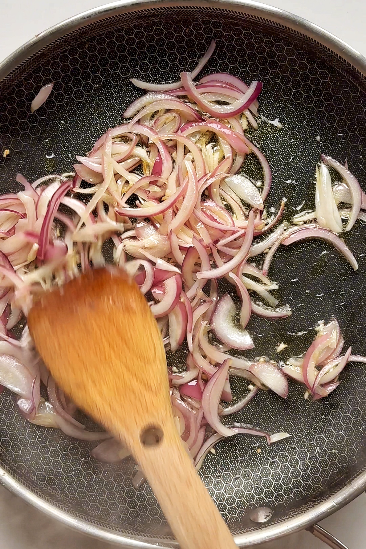 Frying red onion with garlic in a pan.