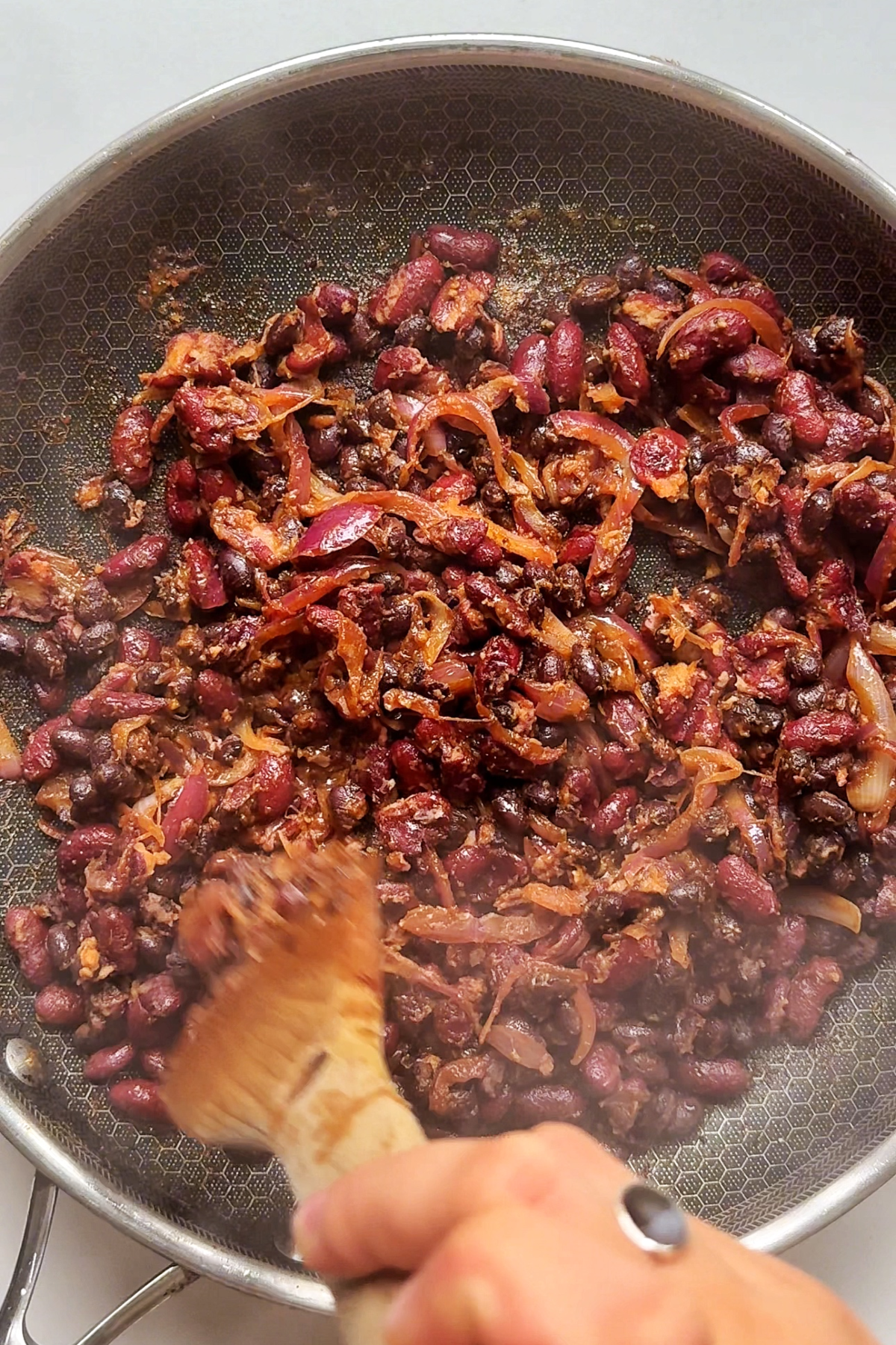 Crushed black beans and kidney beans in a pan for bean tacos.