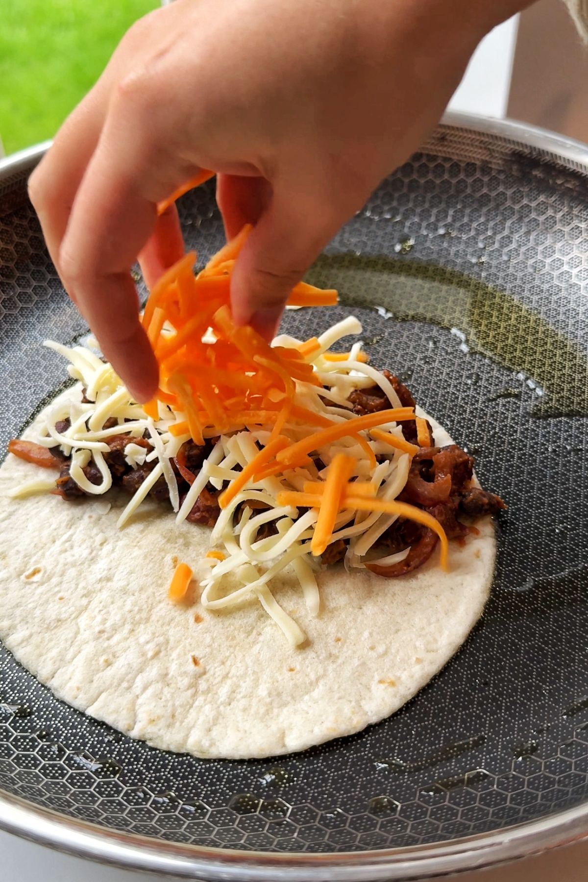 Layering the black bean and kidney bean tacos with cheese.