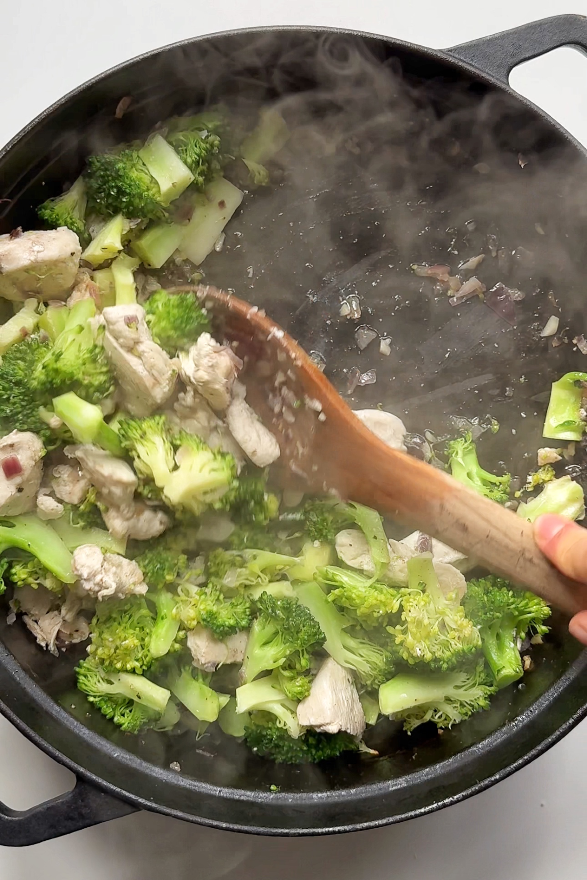 Removing chicken and broccoli from the pan.