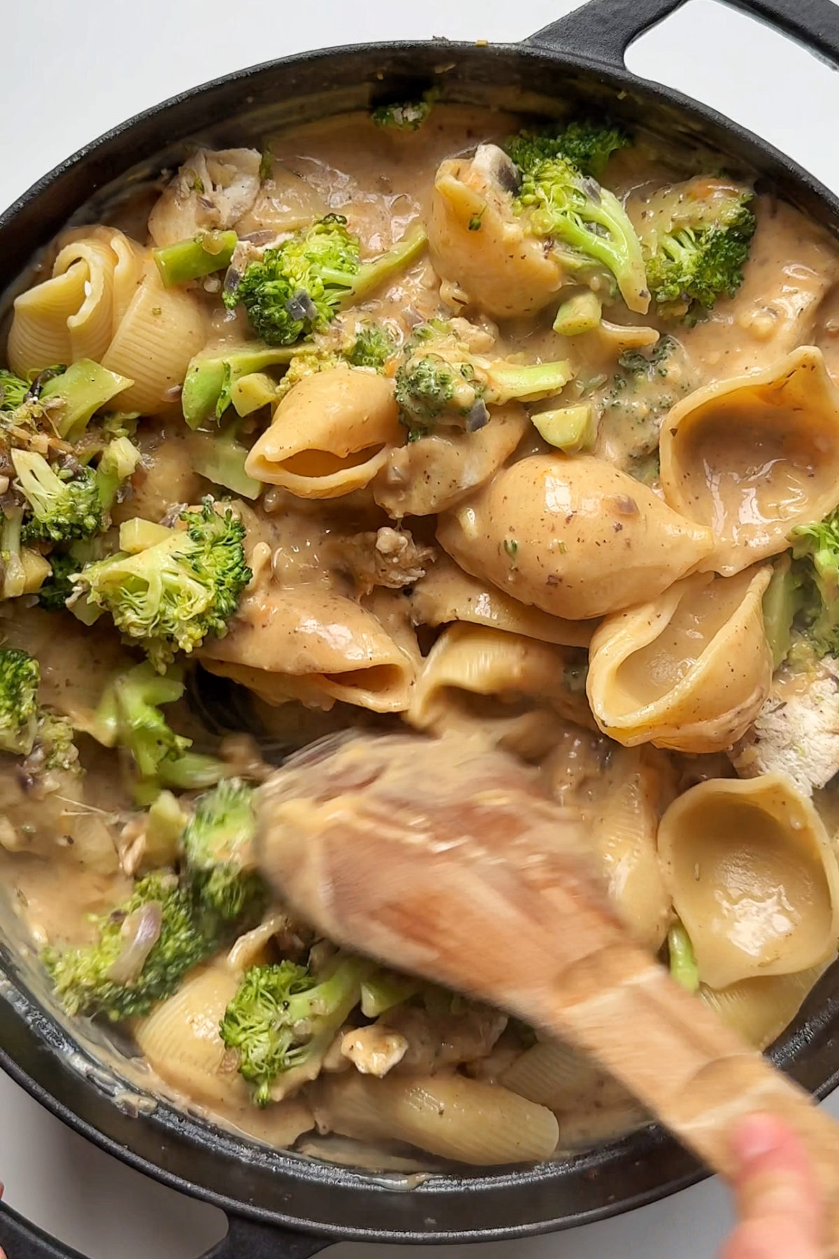 Stirring chicken and broccoli pasta.