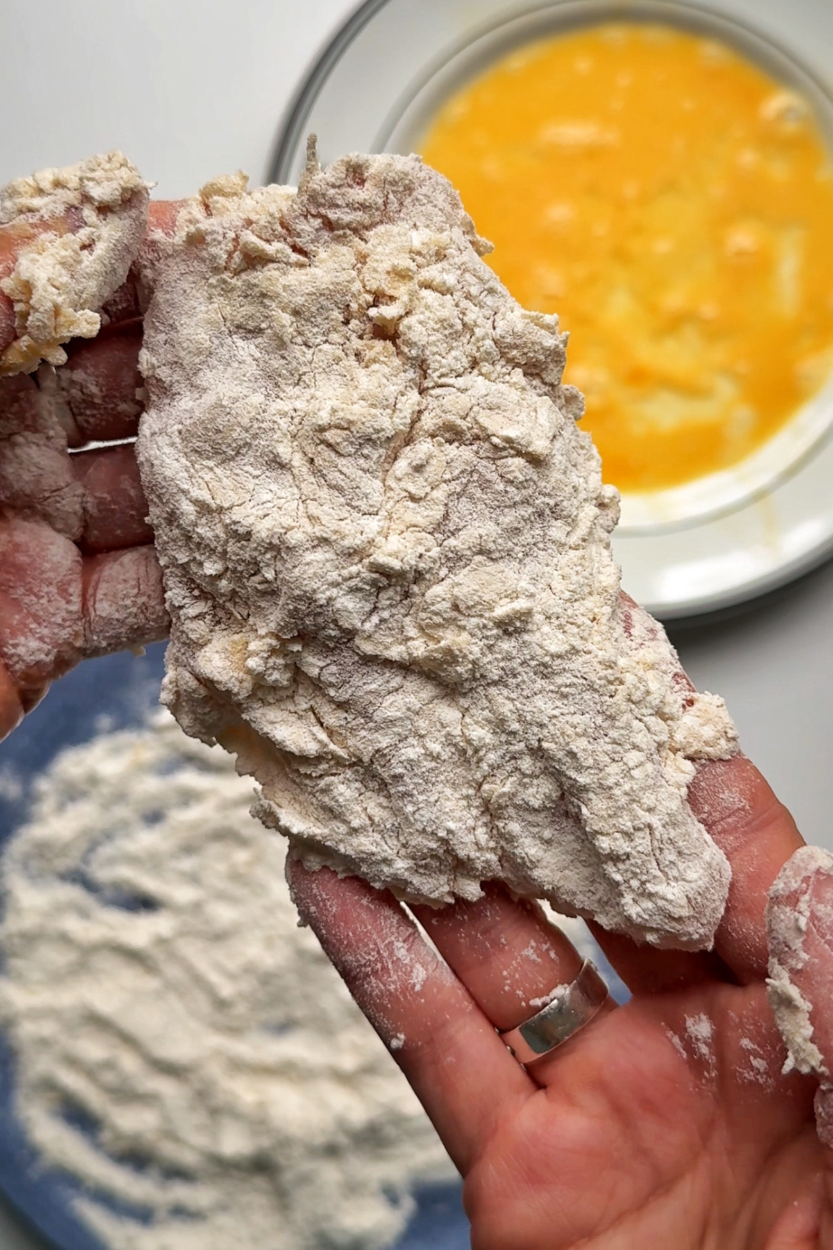 Coating chicken in egg and flour.