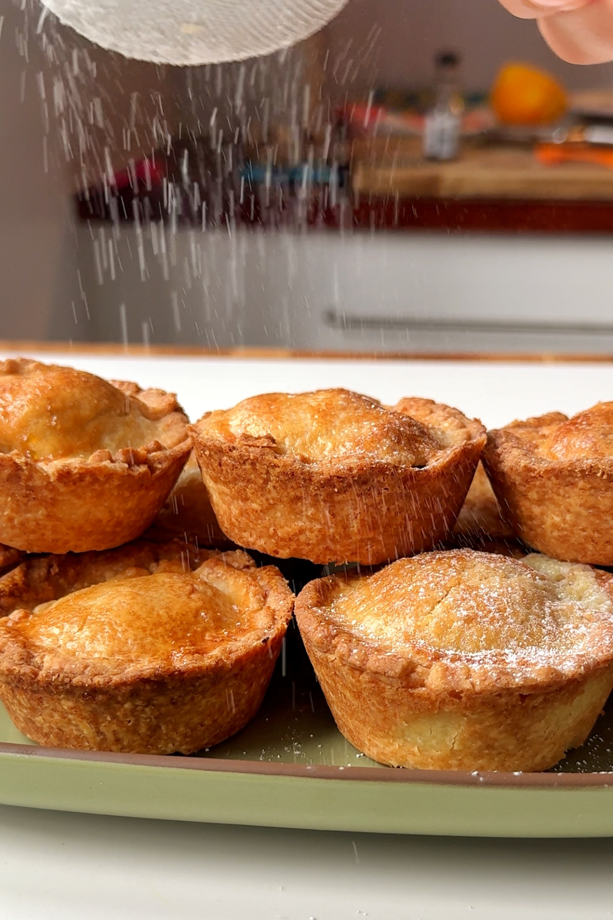 Sprinkling the mince pies with icing sugar.