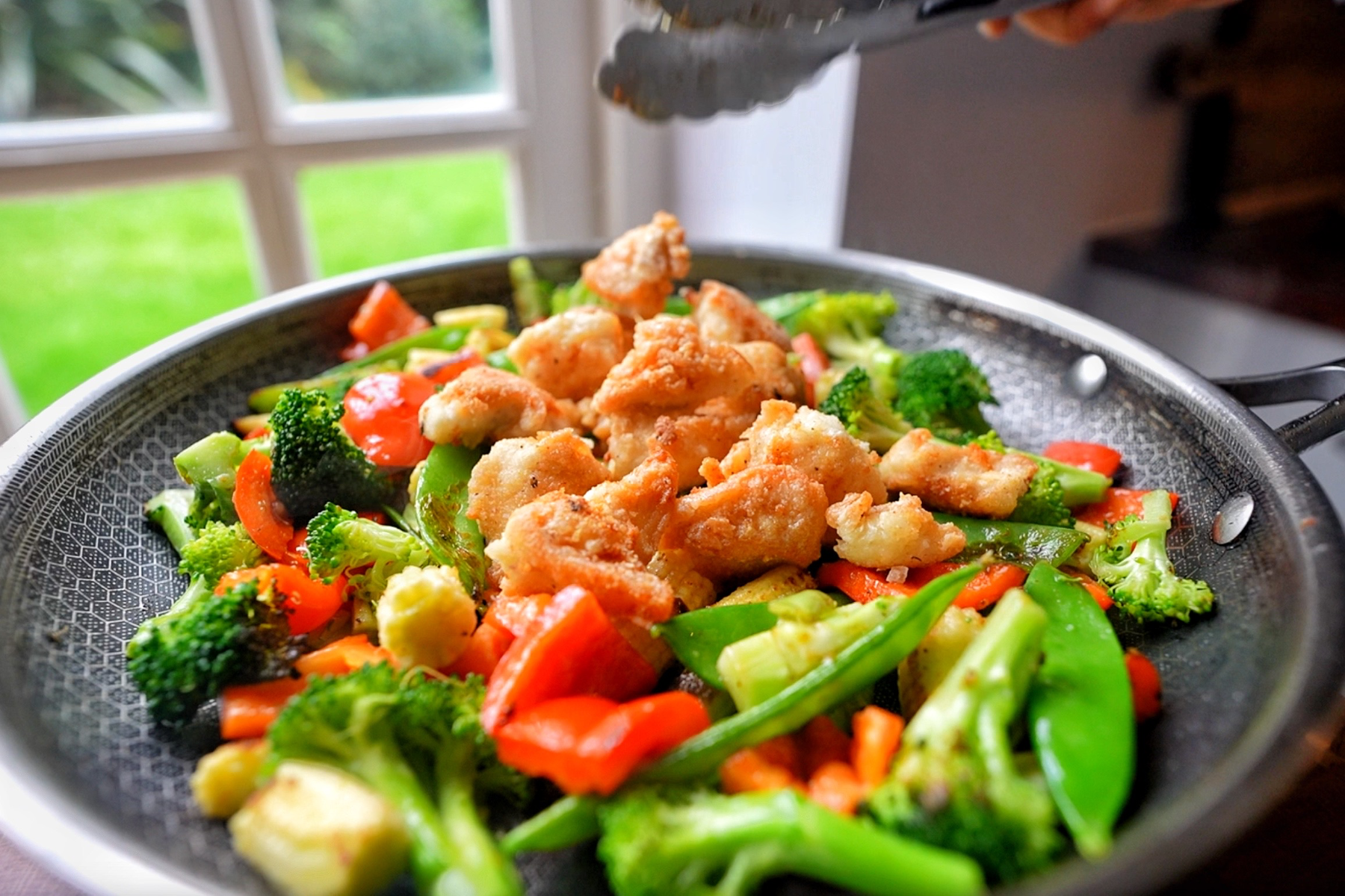 Adding fried chicken to your vegetable pan.