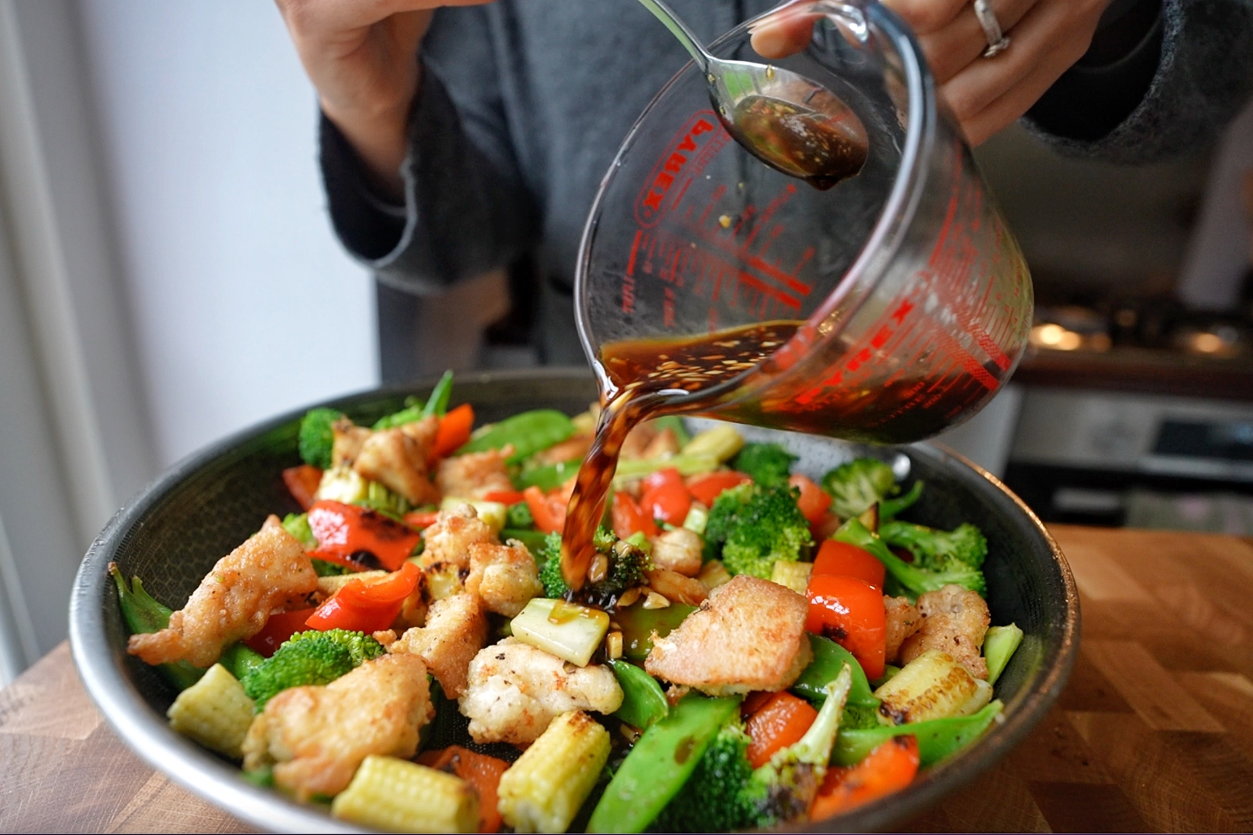 Pouring your teriyaki sauce into the chicken and veggie stir fry.