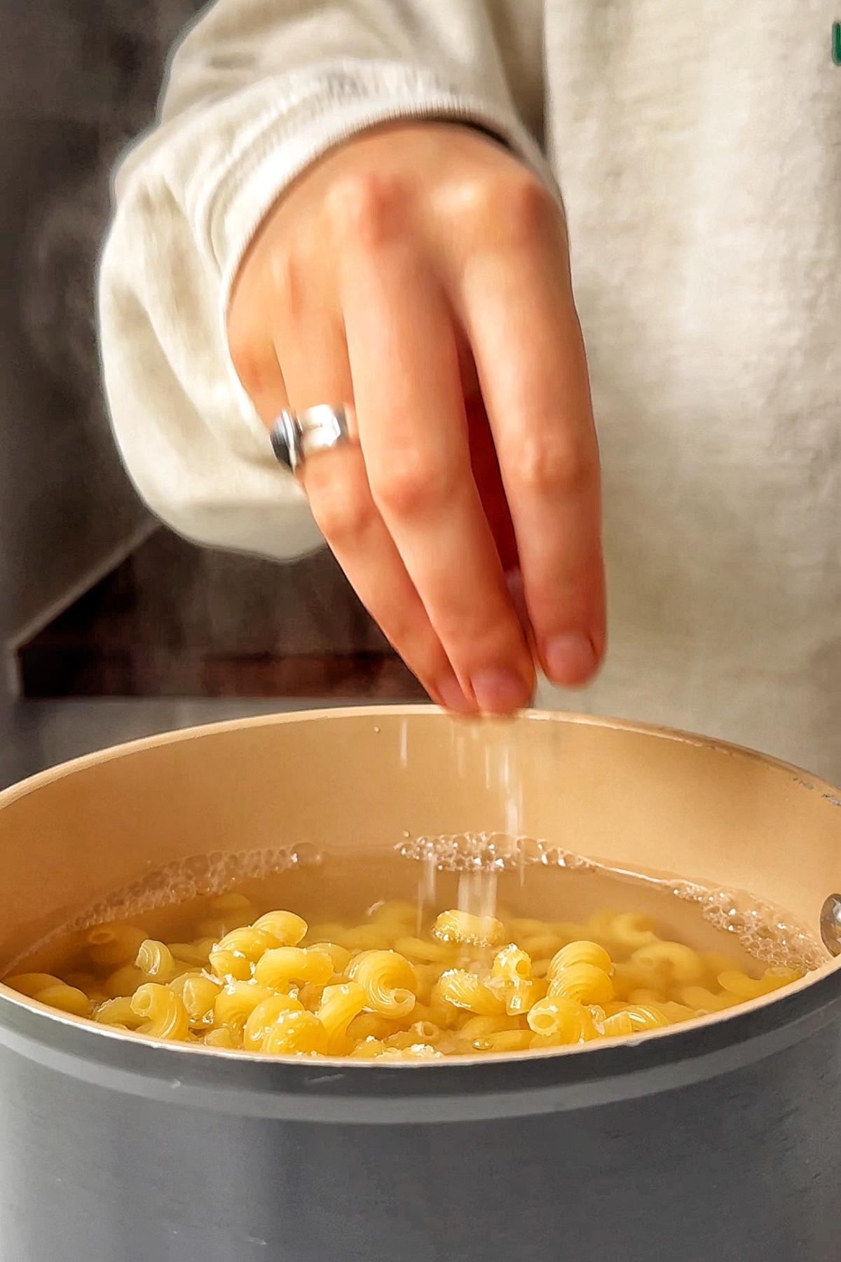 cooking macaroni pasta in a pan with a pinch of salt.